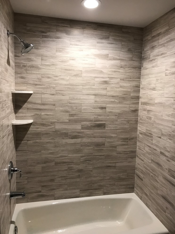 Foto di una stanza da bagno tradizionale di medie dimensioni con vasca ad alcova, vasca/doccia, piastrelle grigie e piastrelle in gres porcellanato