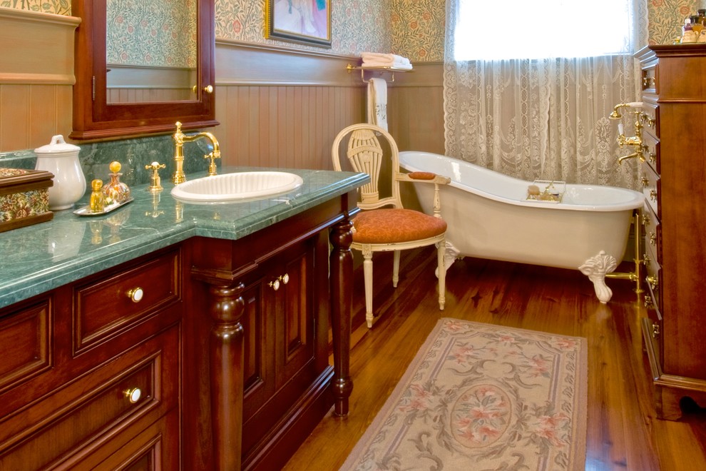 Aménagement d'une salle d'eau classique en bois foncé de taille moyenne avec un lavabo posé, un placard avec porte à panneau encastré, une baignoire sur pieds, un mur vert, un sol en bois brun, un plan de toilette en marbre et un plan de toilette turquoise.