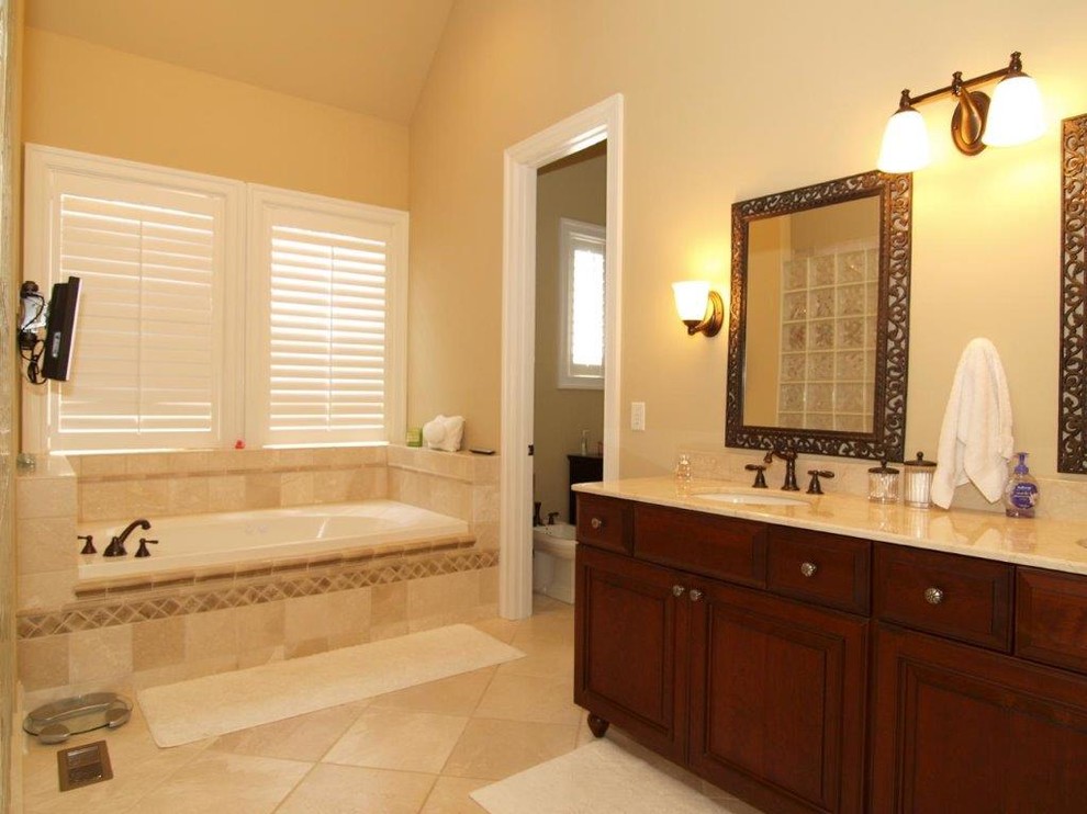 Exempel på ett mellanstort klassiskt badrum, med ett nedsänkt handfat, luckor med upphöjd panel, skåp i mörkt trä, granitbänkskiva, ett platsbyggt badkar, beige kakel, keramikplattor, beige väggar, vinylgolv och en toalettstol med separat cisternkåpa