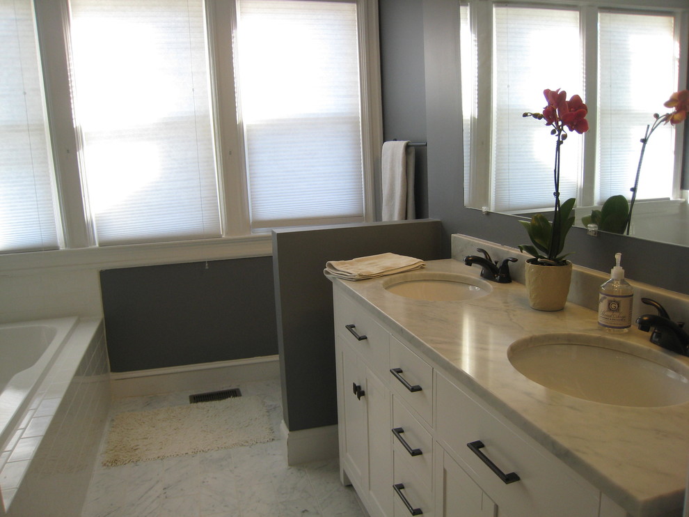 Exempel på ett modernt badrum, med släta luckor, vita skåp, ett platsbyggt badkar, en hörndusch, en toalettstol med separat cisternkåpa, vit kakel, keramikplattor, beige väggar, marmorgolv, ett undermonterad handfat och marmorbänkskiva