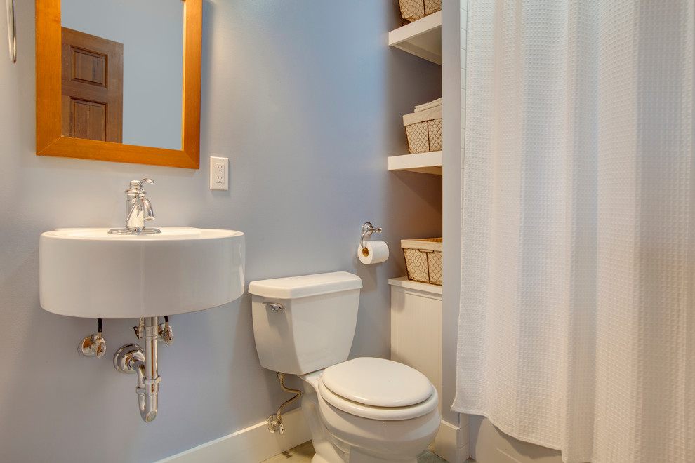 Idee per una piccola stanza da bagno con doccia stile marinaro con lavabo sospeso, consolle stile comò, ante bianche, vasca ad alcova, piastrelle bianche, piastrelle di ciottoli, pareti blu e pavimento in gres porcellanato