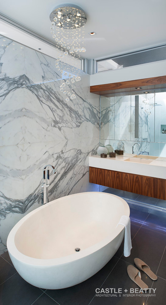 Cette image montre une salle de bain design en bois brun avec un lavabo intégré, un placard à porte plane, une baignoire indépendante et une douche d'angle.