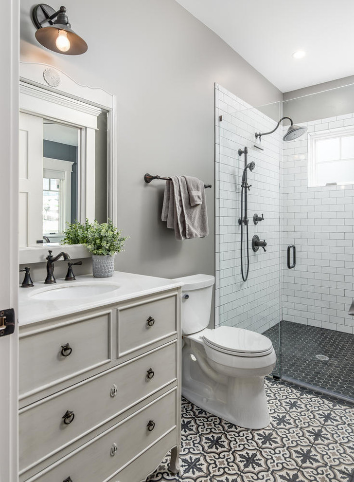 Exempel på ett mellanstort amerikanskt vit vitt badrum med dusch, med luckor med profilerade fronter, grå skåp, en kantlös dusch, en toalettstol med separat cisternkåpa, vit kakel, porslinskakel, grå väggar, cementgolv, ett undermonterad handfat, bänkskiva i kvartsit, svart golv och dusch med gångjärnsdörr