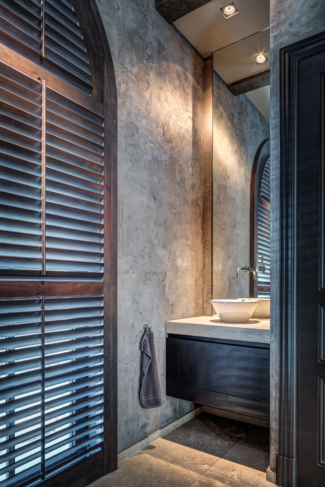 Foto de cuarto de baño actual con lavabo sobreencimera, armarios con paneles lisos, puertas de armario de madera en tonos medios y paredes grises