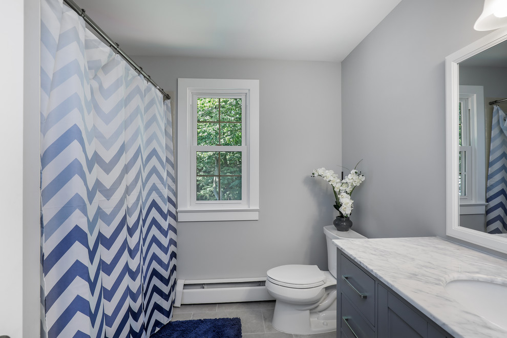 This is an example of a medium sized traditional bathroom in Cleveland with shaker cabinets, grey cabinets, an alcove bath, a shower/bath combination, a one-piece toilet, white walls, a submerged sink, grey floors, a shower curtain and white worktops.
