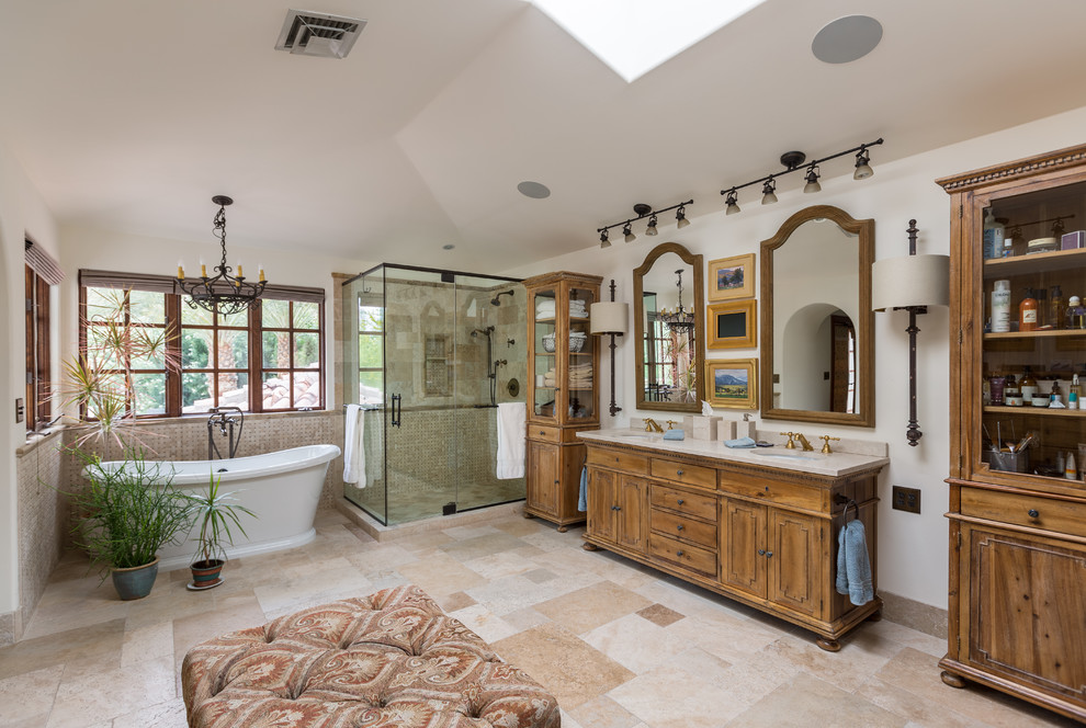 Cette photo montre une grande salle de bain principale méditerranéenne en bois brun avec une douche d'angle, un carrelage beige, un carrelage de pierre, un mur blanc, un lavabo encastré et un plan de toilette en marbre.