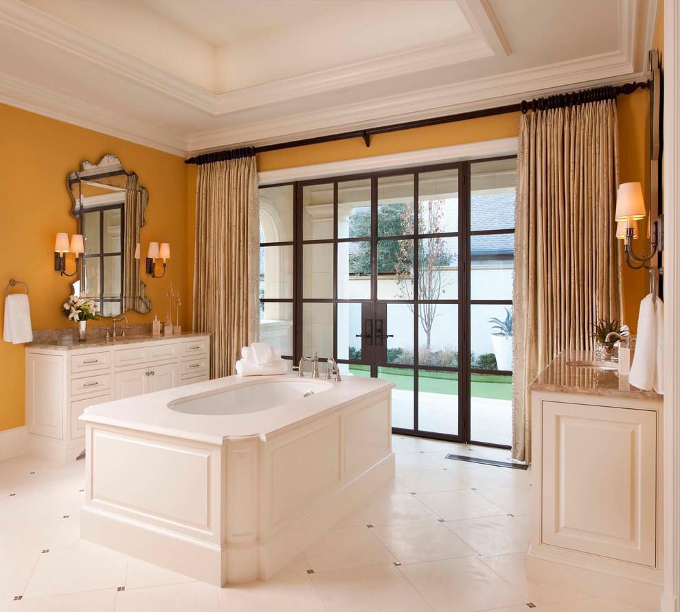 Cette photo montre une salle de bain méditerranéenne avec un lavabo encastré, un placard avec porte à panneau surélevé, des portes de placard blanches, une baignoire encastrée et un mur jaune.