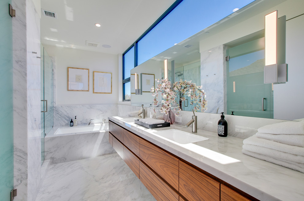 Photo of a contemporary bathroom in Los Angeles with flat-panel cabinets, medium wood cabinets, an alcove shower, white walls, a submerged sink, white floors, a hinged door, grey worktops, double sinks and a floating vanity unit.