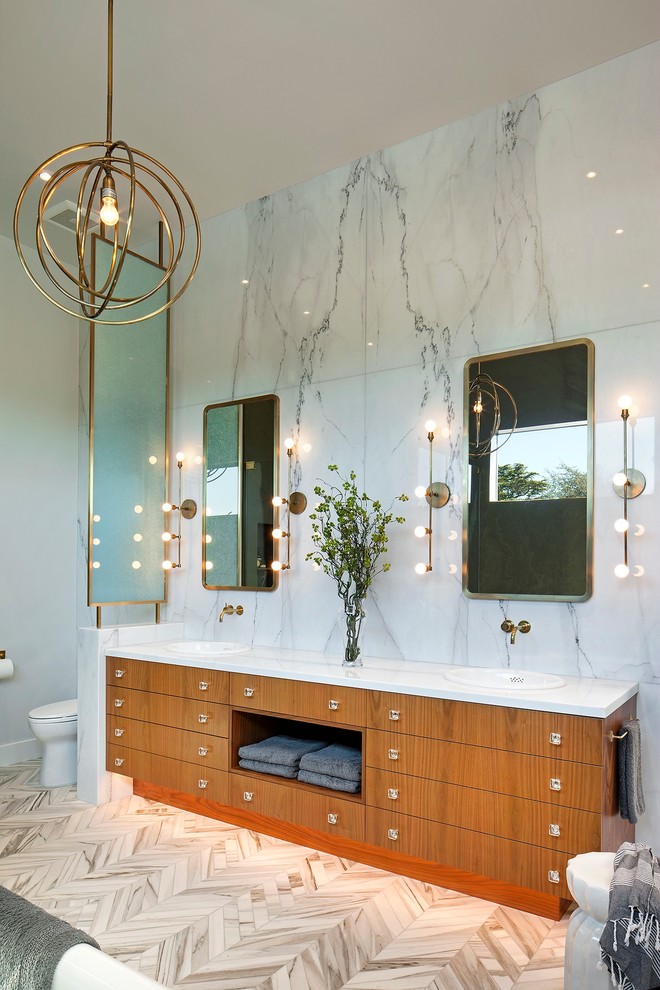 Пример оригинального дизайна: большая главная ванная комната в современном стиле с плоскими фасадами, фасадами цвета дерева среднего тона, отдельно стоящей ванной, душем без бортиков, унитазом-моноблоком, серой плиткой, плиткой из известняка, серыми стенами, мраморным полом, врезной раковиной, мраморной столешницей, разноцветным полом и душем с распашными дверями