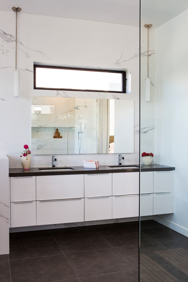 Exempel på ett stort modernt svart svart en-suite badrum, med släta luckor, vita skåp, ett fristående badkar, en dusch/badkar-kombination, vit kakel, marmorkakel, vita väggar, klinkergolv i porslin, ett undermonterad handfat, bänkskiva i akrylsten, grått golv och med dusch som är öppen