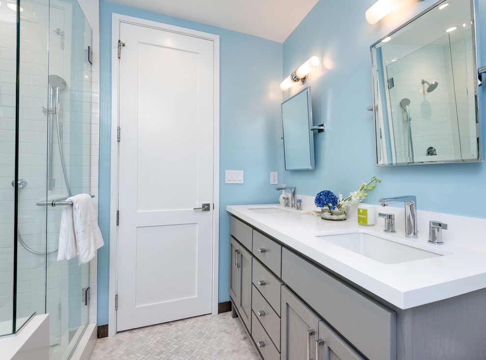 Modelo de cuarto de baño marinero con armarios estilo shaker, ducha esquinera, paredes azules, lavabo bajoencimera y puertas de armario grises