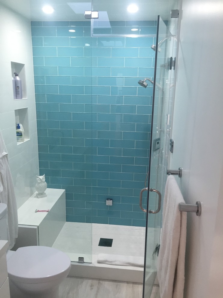 Esempio di una stanza da bagno padronale minimalista di medie dimensioni con ante lisce, ante bianche, vasca freestanding, piastrelle blu, piastrelle di vetro, pareti bianche, pavimento con piastrelle in ceramica, doccia alcova e pavimento grigio