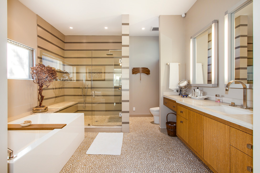 Cette photo montre une douche en alcôve principale tendance en bois brun avec un placard à porte plane, une baignoire indépendante, un carrelage multicolore, un mur beige, un sol en galet et un lavabo encastré.