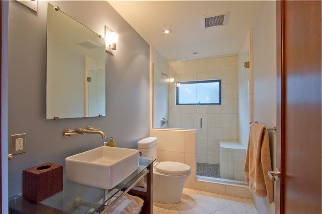 Exemple d'une petite salle de bain tendance avec WC à poser, des carreaux de céramique, un mur gris, un sol en carrelage de céramique, une vasque et un plan de toilette en verre.