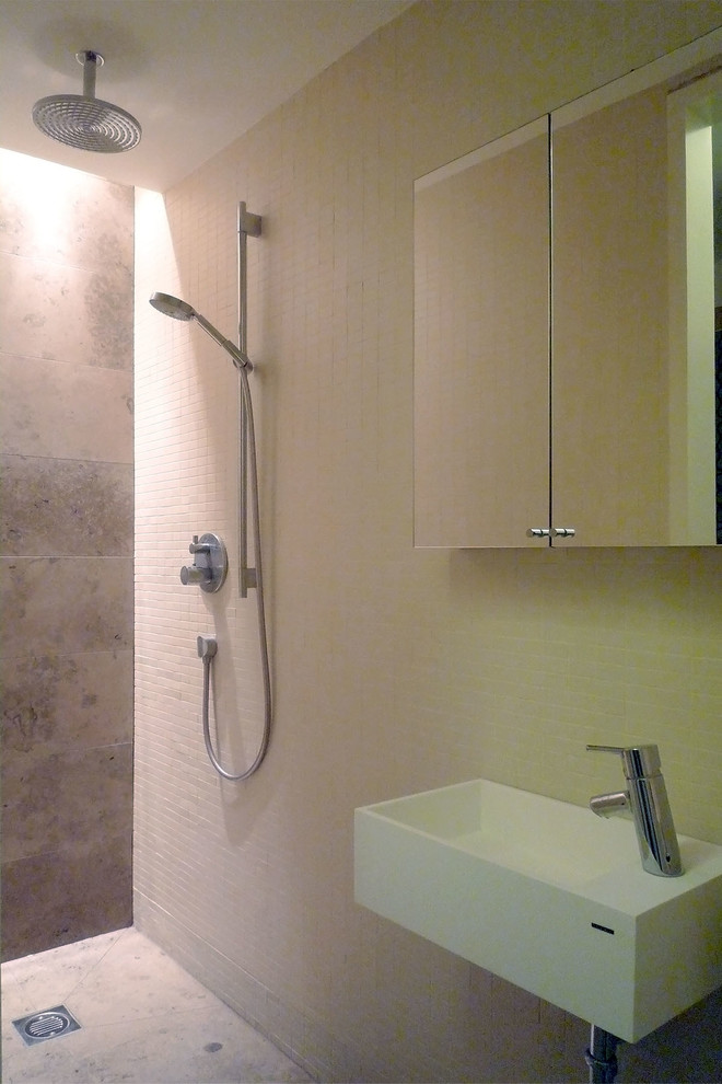 Idéer för att renovera ett litet funkis badrum med dusch, med ett väggmonterat handfat, en dubbeldusch, en vägghängd toalettstol, beige kakel, porslinskakel, beige väggar och kalkstensgolv