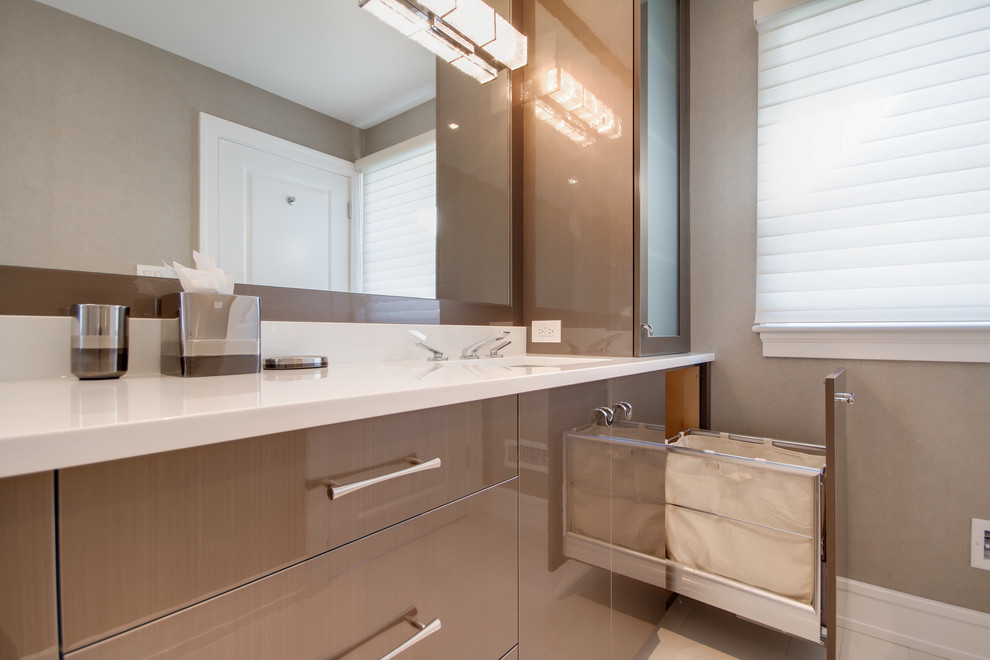 Foto di una stanza da bagno design di medie dimensioni con ante lisce, ante in legno scuro, pareti grigie, lavabo sottopiano e top in superficie solida
