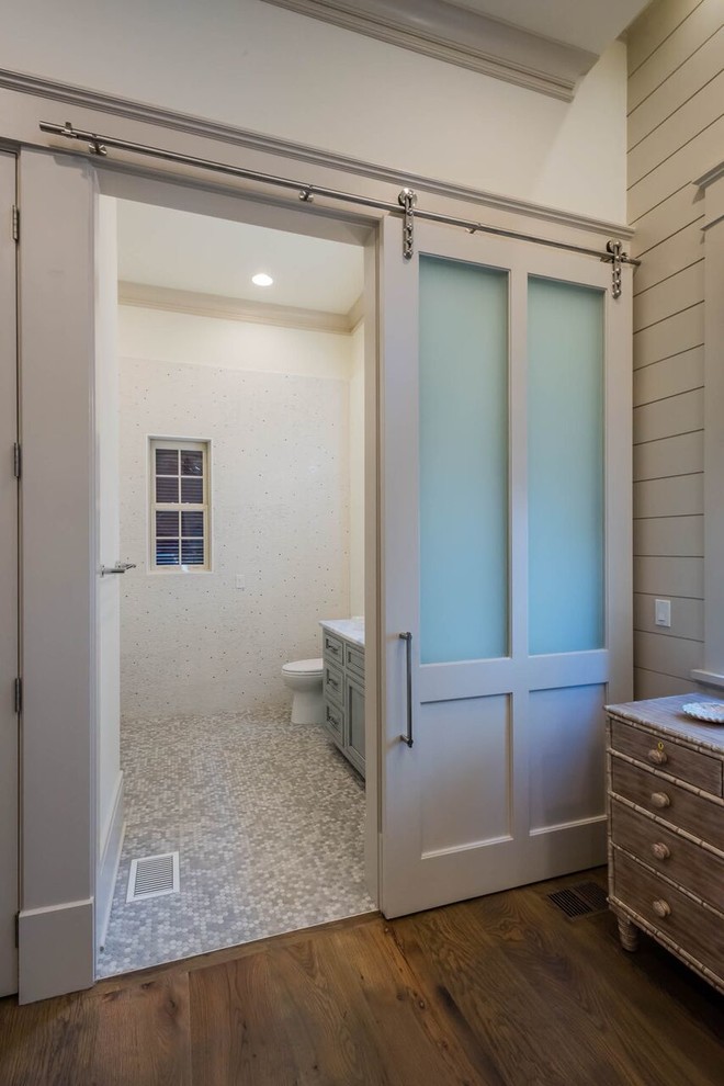 Cette photo montre une salle d'eau chic en bois vieilli de taille moyenne avec un placard à porte affleurante, WC à poser, un carrelage gris, un carrelage blanc, un carrelage en pâte de verre, un mur blanc, un sol en galet, un lavabo encastré et un plan de toilette en marbre.