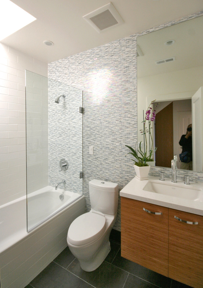 Photo of a small traditional bathroom in San Francisco with flat-panel cabinets, light wood cabinets, an alcove bath, a shower/bath combination, multi-coloured tiles, matchstick tiles, porcelain flooring, a submerged sink, engineered stone worktops, grey floors and a hinged door.