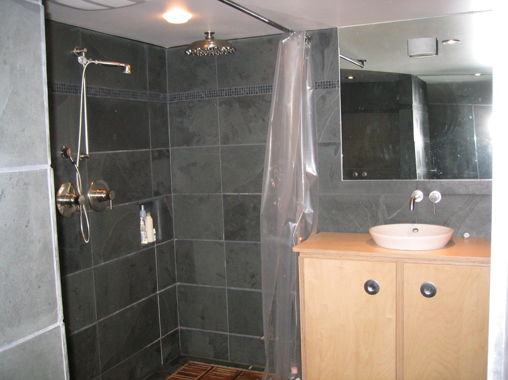Idéer för ett mellanstort modernt en-suite badrum, med ett fristående handfat, luckor med upphöjd panel, skåp i ljust trä, träbänkskiva, en dubbeldusch, en vägghängd toalettstol, svart kakel, stenhäll, svarta väggar och skiffergolv