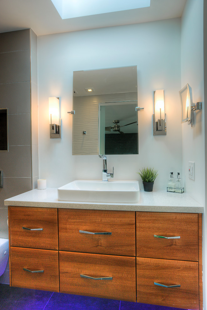 Photo of a medium sized modern bathroom with white tiles, white walls, medium wood cabinets, an alcove shower, a wall mounted toilet, ceramic tiles, ceramic flooring, a trough sink and quartz worktops.