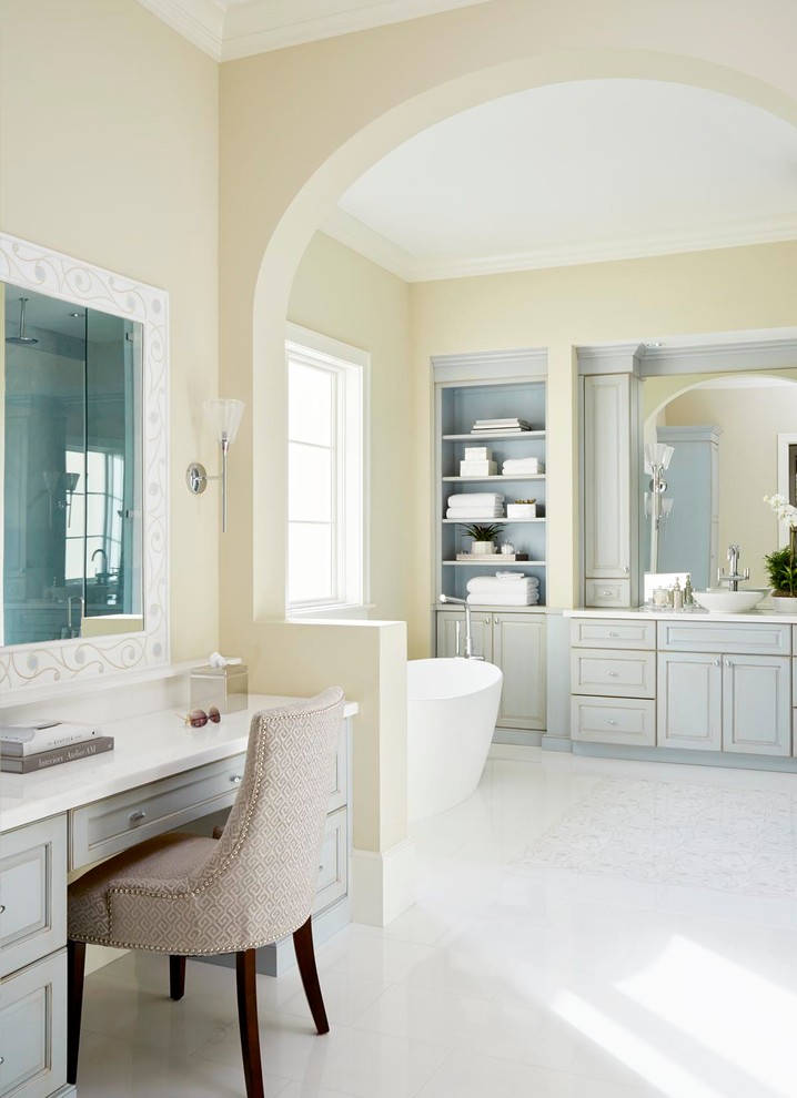 マイアミにあるビーチスタイルのおしゃれな浴室 (レイズドパネル扉のキャビネット、グレーのキャビネット、置き型浴槽、黄色い壁、ベッセル式洗面器、白い床) の写真