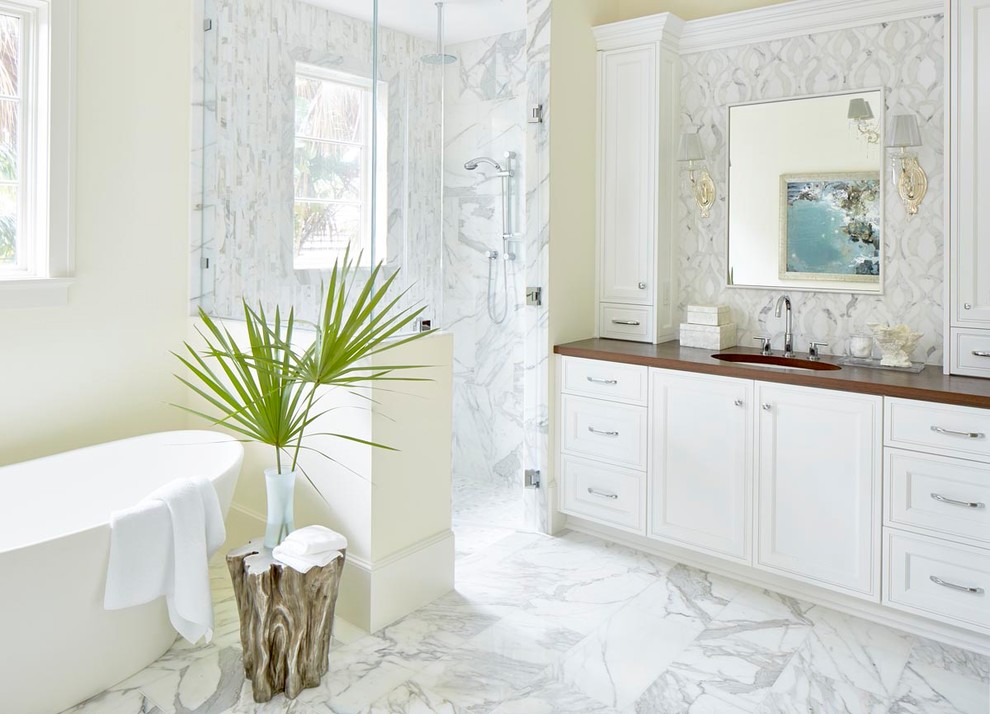 Exempel på ett maritimt badrum, med luckor med infälld panel, vita skåp, ett fristående badkar, en hörndusch, vit kakel, beige väggar, ett undermonterad handfat, vitt golv och dusch med gångjärnsdörr