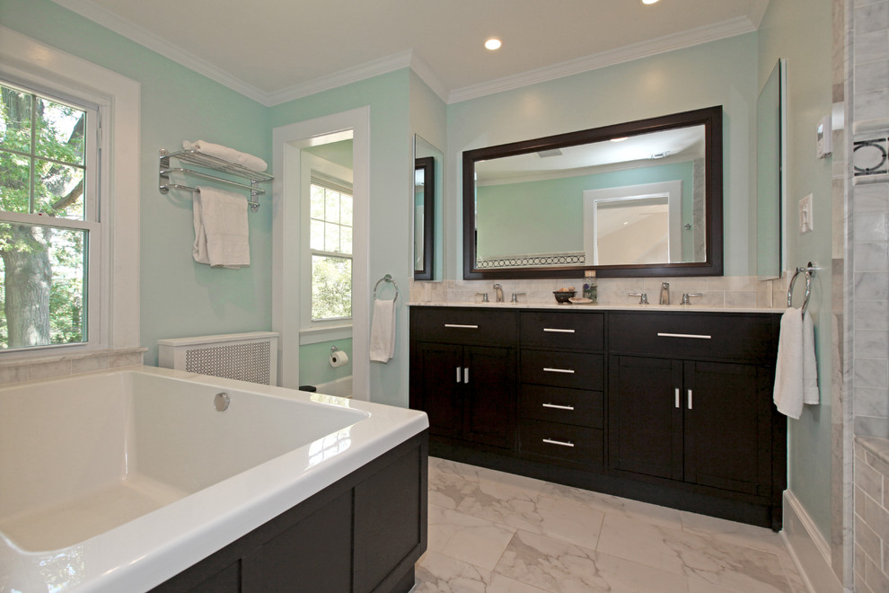 Example of a trendy gray tile drop-in bathtub design in Newark with shaker cabinets and dark wood cabinets