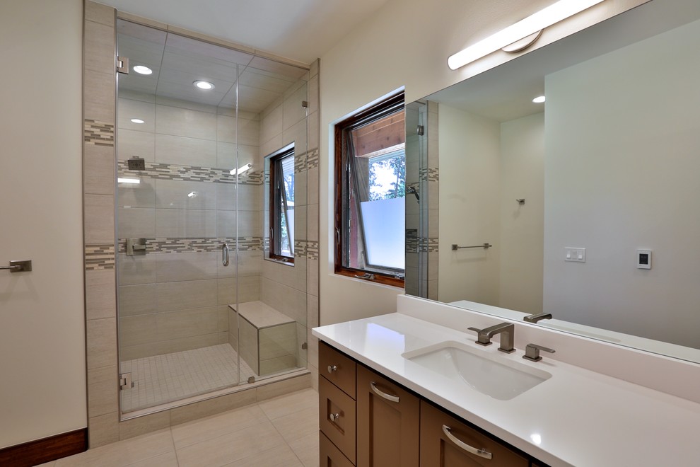 Example of a mid-sized transitional master white tile and porcelain tile porcelain tile and gray floor corner shower design in Other with recessed-panel cabinets, brown cabinets, a two-piece toilet, an undermount sink, quartzite countertops, white walls, a hinged shower door and white countertops
