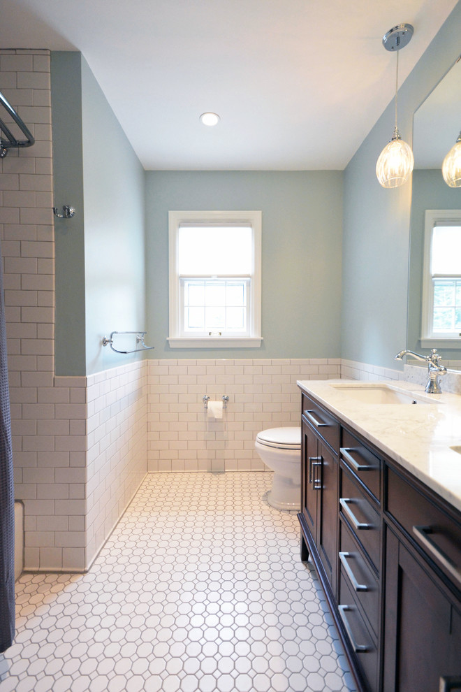 Cette image montre une salle de bain traditionnelle en bois brun de taille moyenne pour enfant avec un lavabo encastré, un placard à porte shaker, un plan de toilette en marbre, WC à poser, un carrelage blanc, des carreaux de porcelaine, un mur bleu et un sol en carrelage de terre cuite.