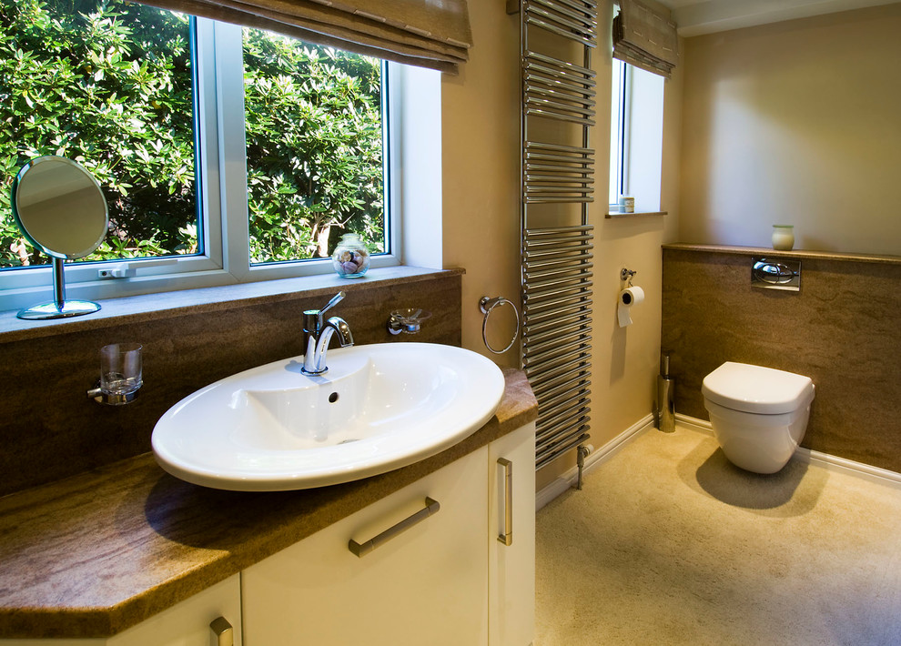 Cette photo montre une salle de bain chic de taille moyenne pour enfant avec une vasque, un placard en trompe-l'oeil, des portes de placard blanches, un plan de toilette en surface solide, une douche ouverte, WC suspendus et un mur beige.