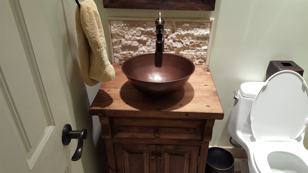 Foto på ett litet rustikt badrum, med ett fristående handfat, möbel-liknande, skåp i slitet trä, träbänkskiva, en toalettstol med hel cisternkåpa, flerfärgad kakel, stenkakel och travertin golv
