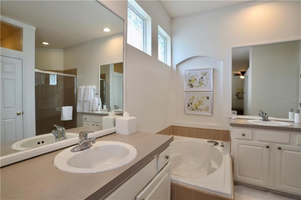 Idées déco pour une salle de bain principale classique de taille moyenne avec un placard avec porte à panneau surélevé, des portes de placard blanches, une baignoire posée, une douche d'angle, WC à poser, un carrelage beige, des carreaux de céramique, un mur blanc, un sol en carrelage de céramique, un lavabo posé, un plan de toilette en stratifié, une cabine de douche à porte coulissante, un plan de toilette gris, meuble double vasque, meuble-lavabo encastré et un sol beige.