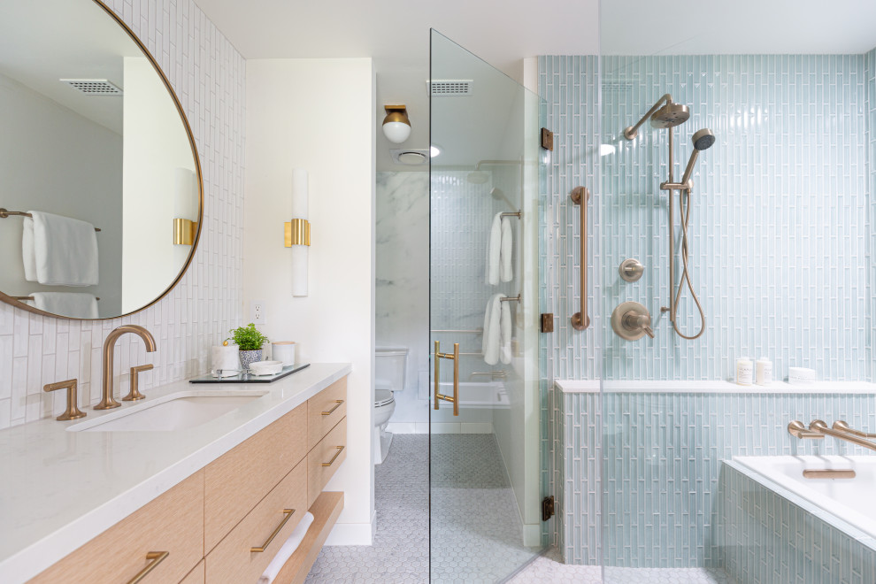 Inspiration for a small contemporary ensuite bathroom in Los Angeles with flat-panel cabinets, light wood cabinets, an alcove bath, a built-in shower, a two-piece toilet, blue tiles, ceramic flooring, a submerged sink, engineered stone worktops, white floors, a hinged door, white worktops, an enclosed toilet, a single sink, glass tiles and a floating vanity unit.