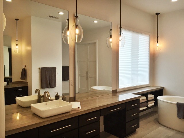 Imagen de cuarto de baño principal minimalista grande con armarios con paneles con relieve, puertas de armario negras, bañera exenta, paredes blancas y lavabo sobreencimera