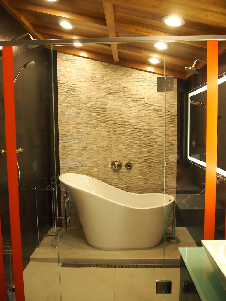 На фото: главная ванная комната среднего размера в современном стиле с плоскими фасадами, черными фасадами, стеклянной столешницей, отдельно стоящей ванной, душевой комнатой, серой плиткой, каменной плиткой, оранжевыми стенами, бетонным полом, настольной раковиной, серым полом, душем с распашными дверями и зеленой столешницей с