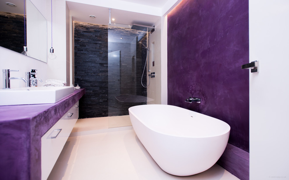 На фото: большая главная ванная комната в современном стиле с отдельно стоящей ванной, открытым душем, инсталляцией, черной плиткой, каменной плиткой, фиолетовыми стенами, полом из керамической плитки и консольной раковиной с