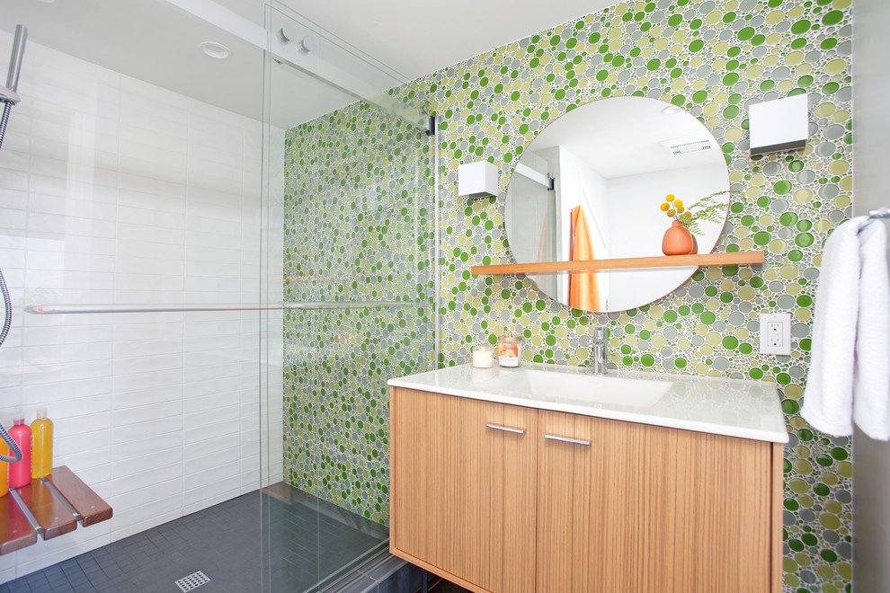 Cette image montre une salle de bain design en bois brun avec un placard à porte plane, un carrelage vert, mosaïque, un lavabo intégré, un sol gris et une cabine de douche à porte coulissante.