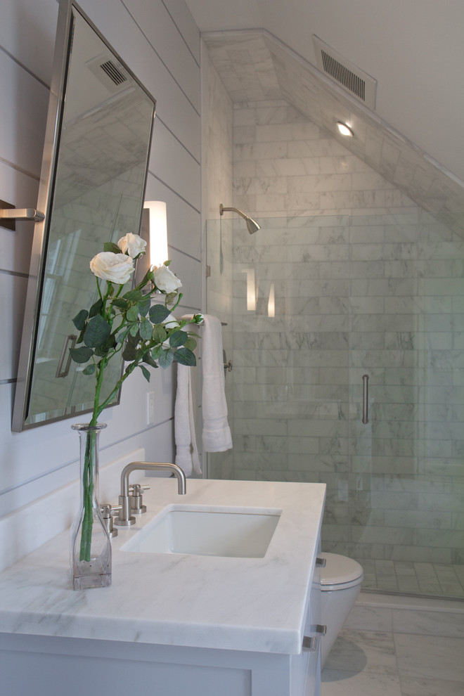 Modelo de cuarto de baño principal campestre de tamaño medio con puertas de armario blancas, ducha empotrada, baldosas y/o azulejos de piedra, paredes blancas, suelo de mármol y lavabo bajoencimera
