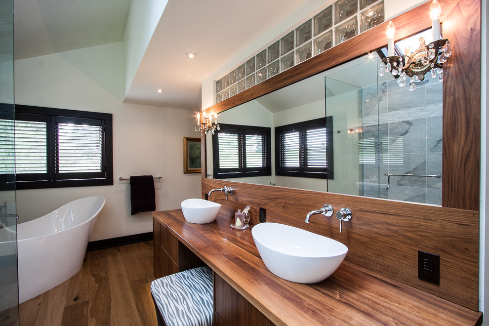 Modernes Badezimmer En Suite mit Aufsatzwaschbecken, flächenbündigen Schrankfronten, dunklen Holzschränken, Waschtisch aus Holz, freistehender Badewanne, Eckdusche, braunem Holzboden und weißer Wandfarbe in Toronto