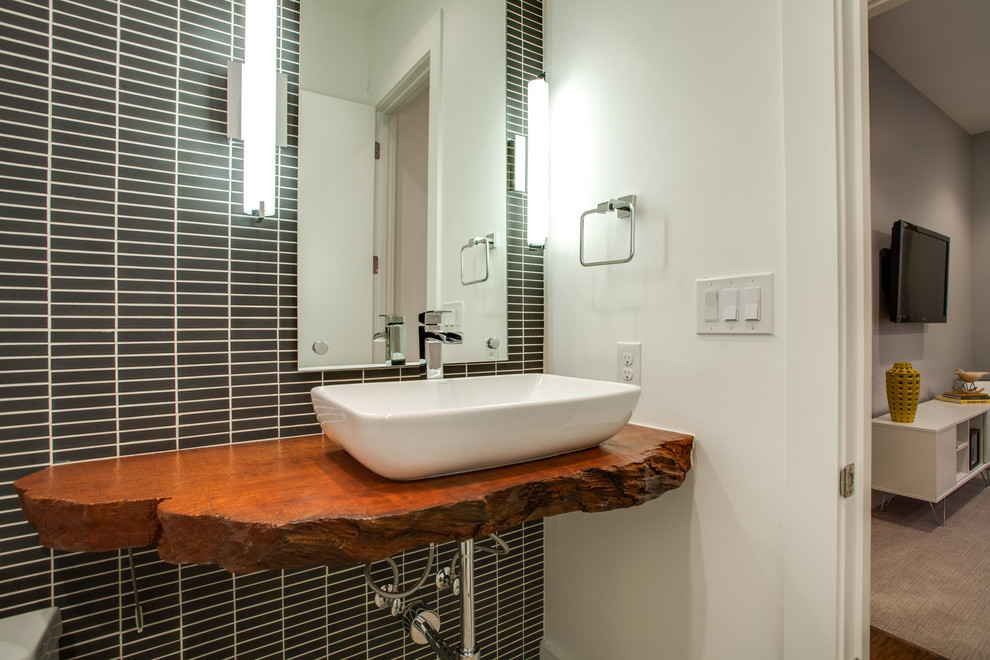 Réalisation d'une salle de bain design avec une vasque et un plan de toilette en bois.