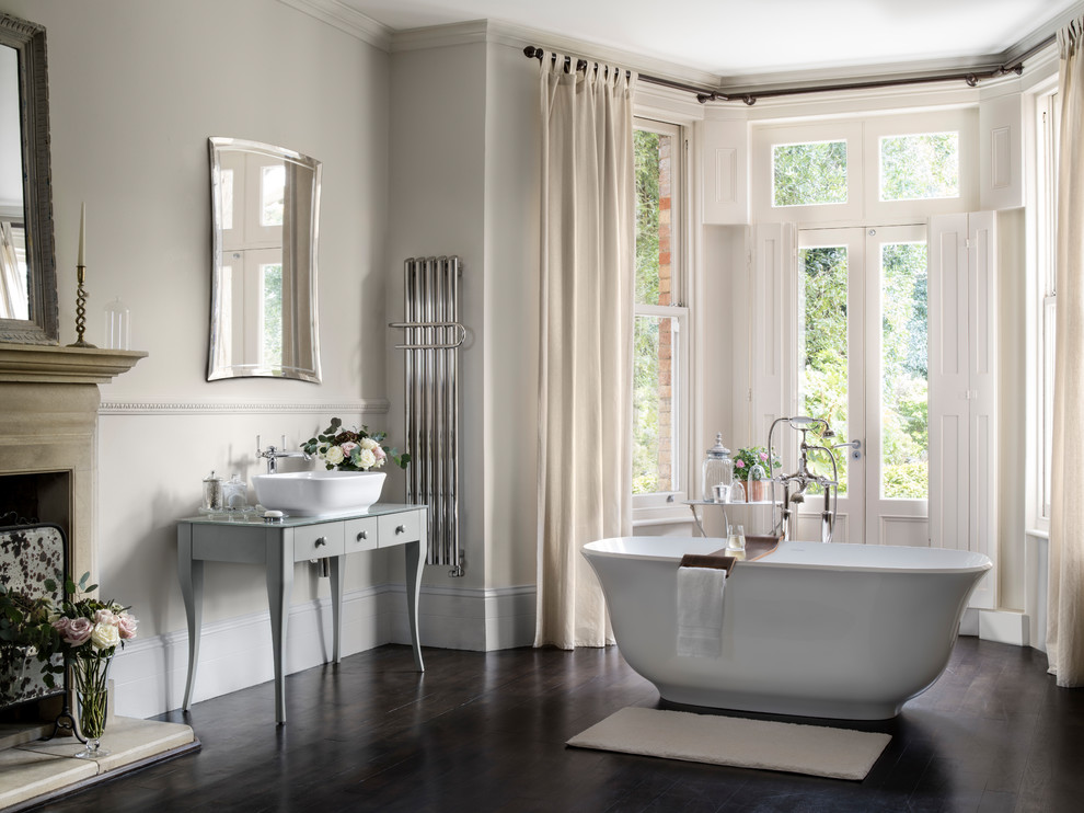 Стильный дизайн: главная ванная комната среднего размера в стиле модернизм с плоскими фасадами, серыми фасадами, отдельно стоящей ванной, серыми стенами, темным паркетным полом, настольной раковиной, стеклянной столешницей и коричневым полом - последний тренд