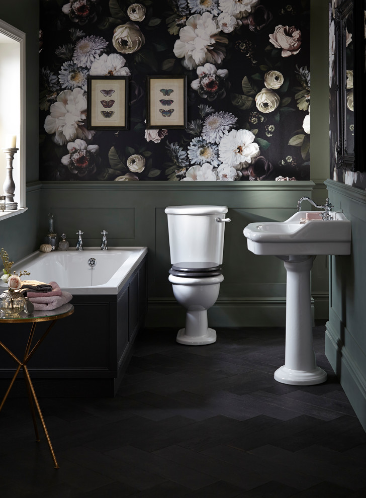 Traditional ensuite bathroom in West Midlands with a built-in bath, a two-piece toilet, multi-coloured walls, dark hardwood flooring, a pedestal sink and black floors.