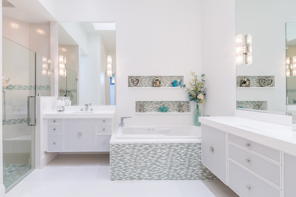 Diseño de cuarto de baño principal contemporáneo de tamaño medio con lavabo bajoencimera, puertas de armario grises, encimera de cuarzo compacto, bañera encastrada, ducha a ras de suelo, sanitario de una pieza, paredes blancas, suelo de baldosas de porcelana y hornacina
