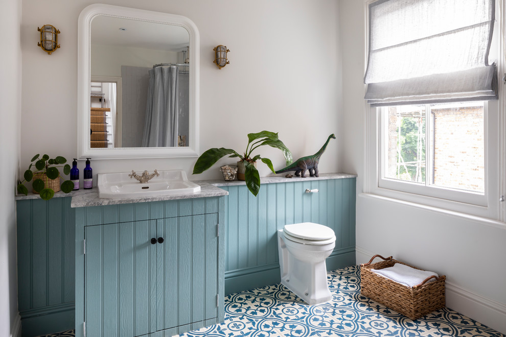 Classic family bathroom in London with granite worktops, blue cabinets, a one-piece toilet, white walls, mosaic tile flooring, a built-in sink, blue floors, grey worktops and flat-panel cabinets.