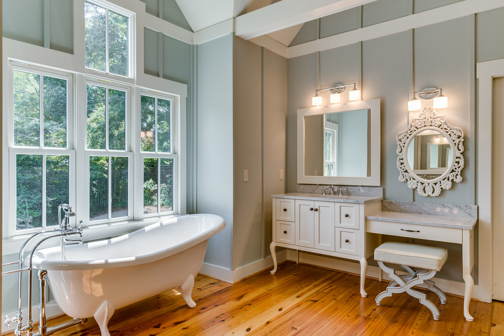 Imagen de cuarto de baño principal clásico con bañera con patas, lavabo bajoencimera, armarios estilo shaker, puertas de armario blancas, ducha empotrada, baldosas y/o azulejos de piedra, suelo de madera en tonos medios y ventanas