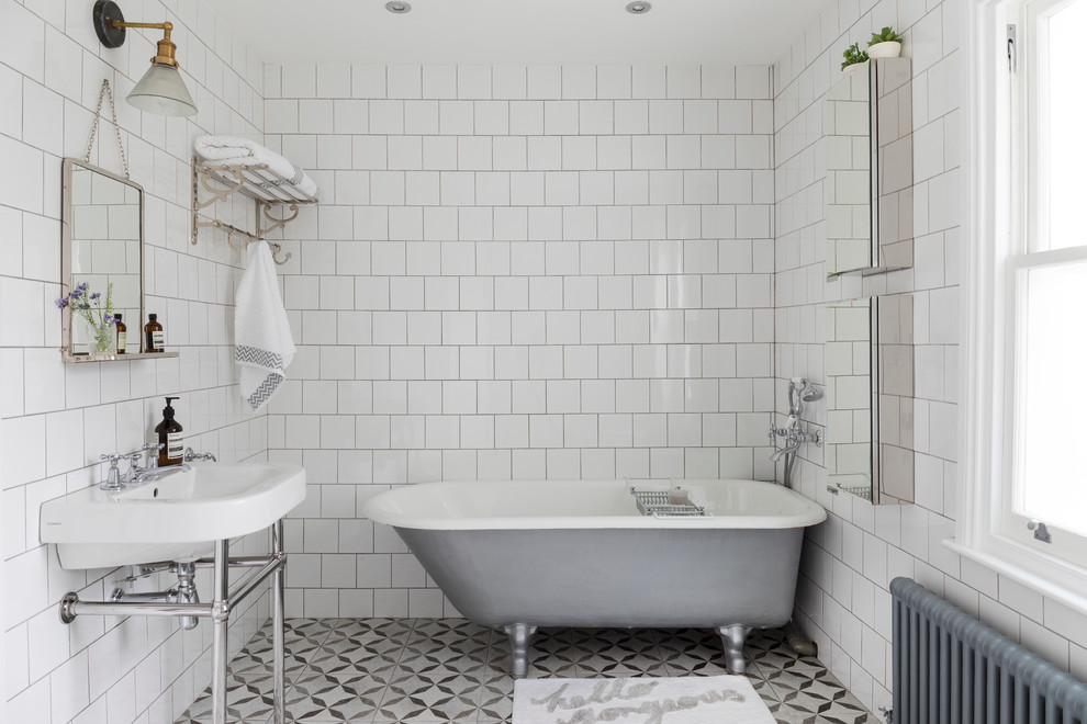 Modelo de cuarto de baño clásico de tamaño medio con bañera exenta, baldosas y/o azulejos blancos, baldosas y/o azulejos de cerámica, paredes blancas, suelo de baldosas de cerámica y lavabo tipo consola