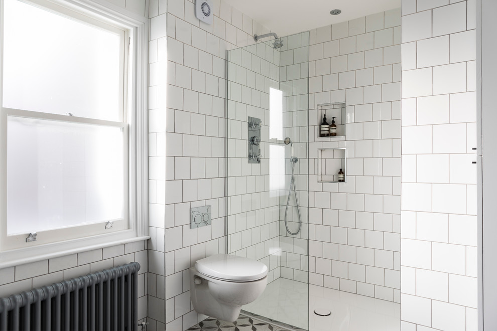This is an example of a medium sized contemporary family bathroom in London with a freestanding bath, a built-in shower, a wall mounted toilet, white tiles, ceramic tiles, white walls, ceramic flooring and a wall-mounted sink.