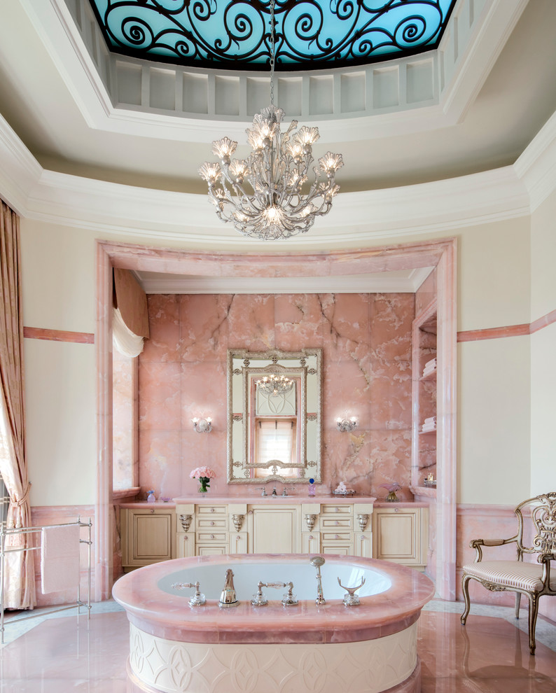 ロサンゼルスにあるヴィクトリアン調のおしゃれなマスターバスルーム (レイズドパネル扉のキャビネット、ベージュのキャビネット、置き型浴槽、ピンクのタイル、ベージュの壁、ピンクの床、ピンクの洗面カウンター) の写真