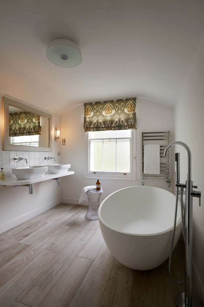 Inspiration for a contemporary ensuite bathroom in Kent with a console sink, solid surface worktops, a freestanding bath, a walk-in shower, a wall mounted toilet, white tiles, white walls and porcelain flooring.