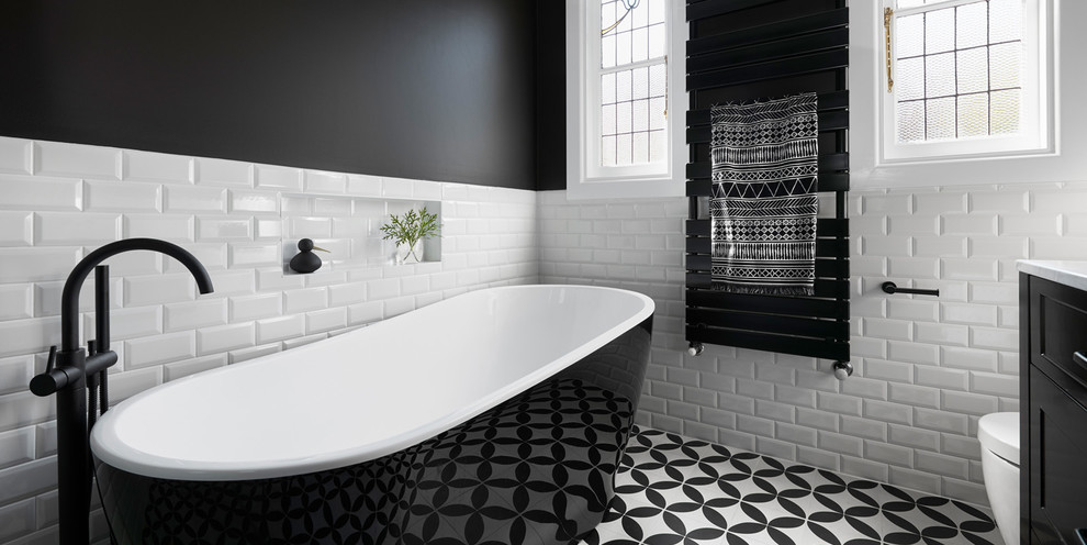 Inredning av ett 60 tals stort en-suite badrum, med möbel-liknande, svarta skåp, ett fristående badkar, en öppen dusch, tunnelbanekakel, mosaikgolv, ett integrerad handfat, marmorbänkskiva och flerfärgat golv
